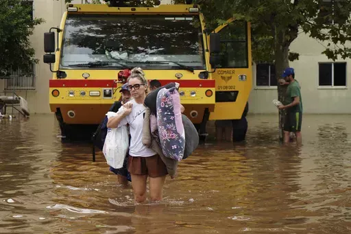 Residents evacuate from a neighborhood flooded by heavy rains, in Canoas, Rio Grande do Sul state, Brazil, Saturday, May 4, 2024. (AP Photo/Carlos Macedo)