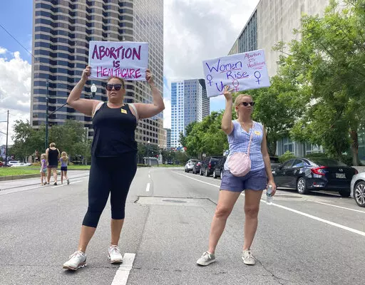 Protesters wave signs and demonstrate in support of abortion access in front of a New Orleans courthouse Friday July 8, 2022. Inside the courthouse a judge was hearing arguments on the state's trigger law designed to outlaw almost all abortions. (AP Photo/Rebecca Santana)