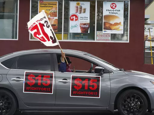 FILE - Fast-food workers drive though a McDonald's restaurant demanding a for a $15 hourly minimum wage in East Los Angeles Friday, March 12, 2021. Minimum wage increases, animal protections, police accountability, cutting and increasing taxes are all part of a series of new laws taking effect across the country on Saturday, the first day of 2022. (AP Photo/Damian Dovarganes, File)