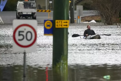 A man paddles his kayak through a flooded street at Windsor on the outskirts of Sydney, Australia, Tuesday, July 5, 2022. Hundreds of homes have been inundated in and around Australia's largest city in a flood emergency that was impacting 50,000 people, officials said Tuesday. (AP Photo/Mark Baker)