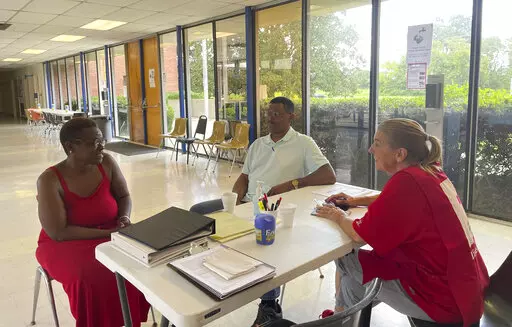 Veronique Daniels, left, speaks to Red Cross volunteers at a temporary shelter for people displaced by central Mississippi flooding, in Jackson, Miss, Sunday, Aug. 28, 2022. Daniels has been homeless for three months and three weeks. She had been sleeping on her mother's back porch when residents in the neighborhood were advised to evacuate. (AP Photo/Michael Goldberg)