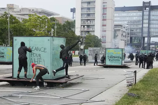 Youth throws a bottle to police forces during riots Thursday, June 29, 2023 in Nanterre, outside Paris. In all, more than 3,600 people have been detained in the unrest across France since the death of Nahel on June 27, with an average age of 17, according to the Interior Ministry. The violence left more than 800 law enforcement officers injured, French courts are working overtime to process the arrests, including opening their doors through the weekend, with fast-track hearings around an hour lo