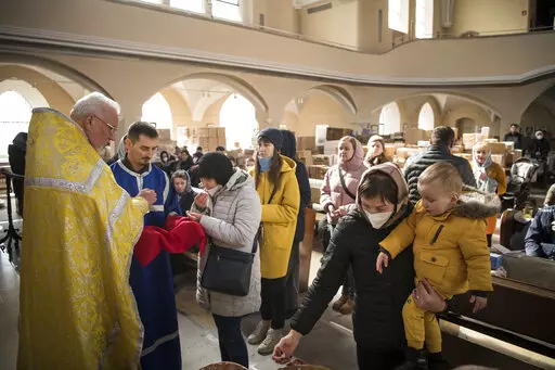Members of the Ukrainian Orthodox community, who have found shelter for their church service in an evangelical church, and refugees from Ukraine celebrate a church service and pray for peace in Berlin, Sunday, March 20, 2022. (AP Photo/Steffi Loos)