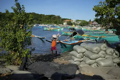 A resident brings down a sack from his boat at the coastal town of Santa Ana, Cagayan province, northern Philippines on Tuesday, May 7, 2024. The United States and the Philippines, which are longtime treaty allies, have identified the far-flung coastal town of Santa Ana in the northeastern tip of the Philippine mainland as one of nine mostly rural areas where rotating batches of American forces could encamp indefinitely and store their weapons and equipment within local military bases under the 