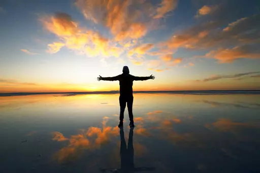 A visitor to Bonneville Salt Flats poses for a photograph pm Sunday, Oct. 9, 2022, near Wendover, Utah. (AP Photo/Rick Bowmer)