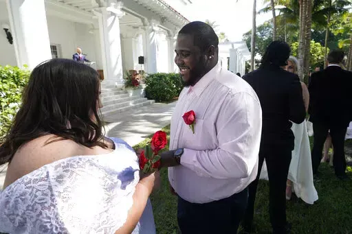 Sarah Horton, left, and Shackeem Frankson exchange rings as they get married during a Valentine's Day group wedding ceremony, Monday, Feb. 14, 2022, outside the Flagler Museum in Palm Beach, Fla. The pair were one of nine couples married by the Clerk of the Circuit Court & Comptroller for Palm Beach County during the annual event. (AP Photo/Wilfredo Lee)