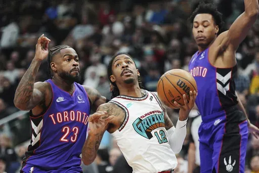 Memphis Grizzlies' Ja Morant (12) drives between Toronto Raptors' Jamal Shead (23) and Toronto Raptors' Scottie Barnes, right during first half NBA basketball action in Toronto on Wednesday, Feb. 5, 2025. (Frank Gunn/The Canadian Press via AP)