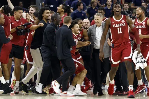 Alabama guard Mark Sears (1) celebrates with teammates and head coach Nate Oats after making a game-wining shot against Auburn in overtime of an NCAA college basketball game, Saturday, March 8, 2025, in Auburn, Ala. (AP Photo/Butch Dill)
