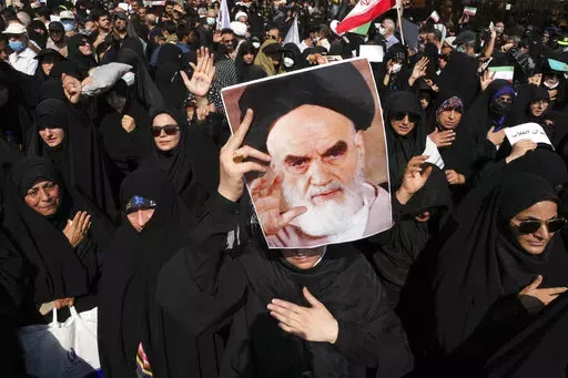 A pro-government demonstrator holds a poster of the late Iranian revolutionary founder Ayatollah Khomeini while attending a rally after the Friday prayers to condemn recent anti-government protests over the death of a young woman in police custody, in Tehran, Iran, Friday, Sept. 23, 2022. The crisis unfolding in Iran began as a public outpouring over the the death of Mahsa Amini, a young woman from a northwestern Kurdish town who was arrested by the country's morality police in Tehran last week 