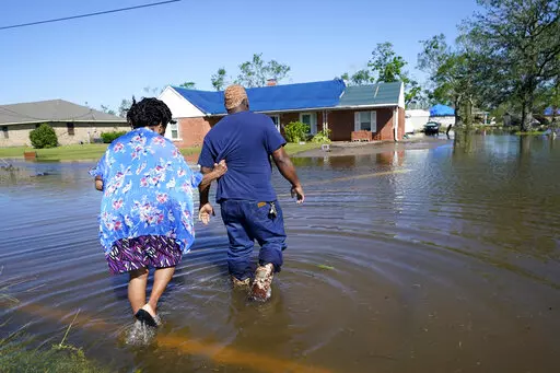 Soncia King holds onto her husband, Patrick King, in Lake Charles, La., Saturday, Oct. 10, 2020, as they walk through the flooded street to their home, after Hurricane Delta moved through the previous day. According to a study published in Nature Communications on Tuesday, April 12, 2022, climate change made the record-smashing deadly 2020 Atlantic hurricane season noticeably wetter. (AP Photo/Gerald Herbert, File)