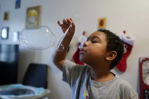 Elijah Hill plays with his bubbles, Saturday, Dec. 11, 2023, in Westfield, Ind. Families reliant on Medicaid worry changes coming in January will limit access to the therapy as Indiana and other states cut the size of the low-income healthcare program.(AP Photo/Darron Cummings)